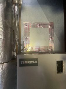 Sheet-metal access plate screwed in place and sealed with foil tape over a duct access port after air duct cleaning